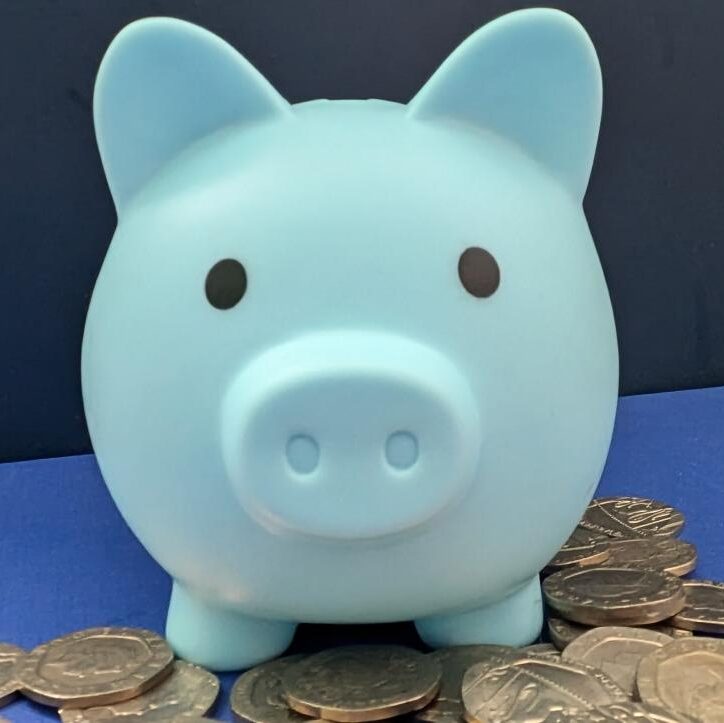 Blue money box pig with twenty pence coins at its feet