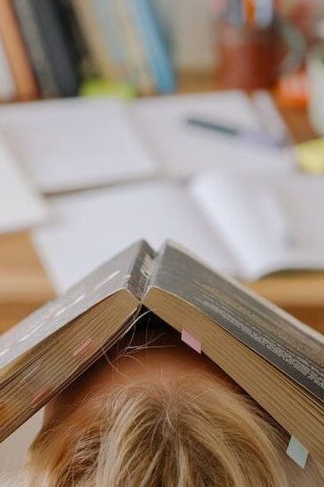 Student sat at their desk with an open book on their head 